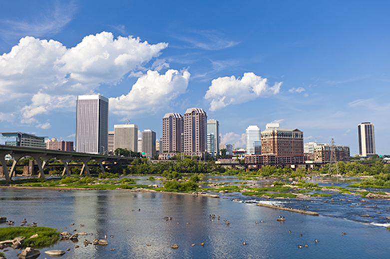 Photo of Richmond from the James River, with tall buildings, small green islands in the river, and people kayaking.
